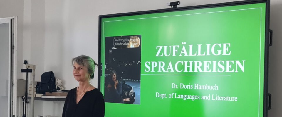 Prof. Dr. Doris Hambuch vor der Präsentationsfolie „Zufällige Sprachreisen“